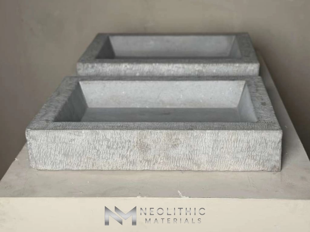 Sinks LA317-24.E.23x16x4 straight-on studio photograph showcasing a pair of rectangular vessel washbasins crafted from light grey speckled stone, stacked front-to-back to highlight their clean geometric profiles and natural textured finish.