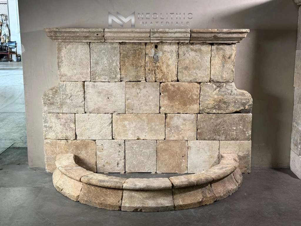 Fountains LC101-01.77x33x54 frontal studio display of a grand architectural wall fountain featuring a high back wall constructed from rustic rectangular stone blocks, an elegant decorative crown molding shelf, and a semi-circular curved pool basin at the base.