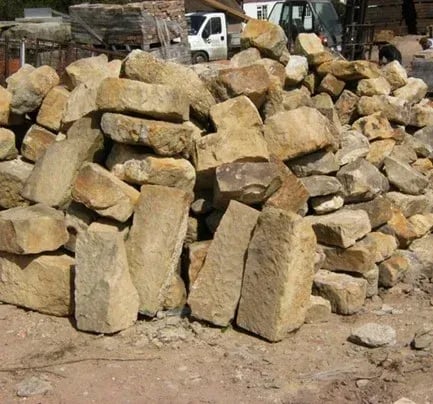 Authentic Reclamation, Pile of rough tan sandstone ballast blocks in a supply yard